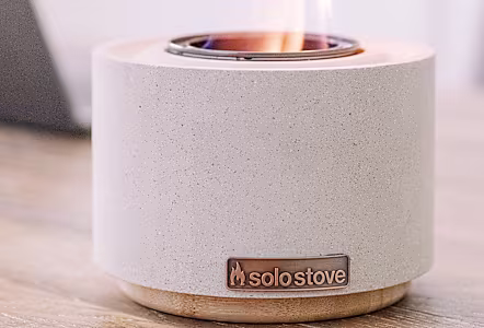 White tabletop fire bowl on a wooden table.